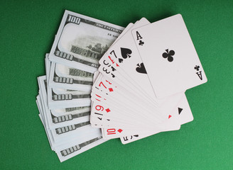 Cards and paper dollars on a table with green cloth