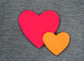 Wooden heart shapes on gray material, in red & gold - concepts of love, good feelings or Valentines, as a background texture with design space.