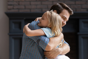Happy adorable preschool blonde girl cuddling young smiling father.