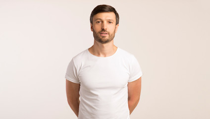 Man Standing With Hands Behind Back Looking At Camera, Isolated