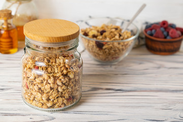 Homemade granola in the glass jar on wooden table in the kitchen