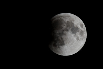 The moon during a lunar eclipse. About one third of the moon is in the shadow of the earth. There is room for text.