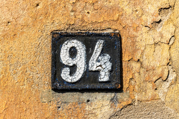 Number 94, ninety four, street number sign on the wall