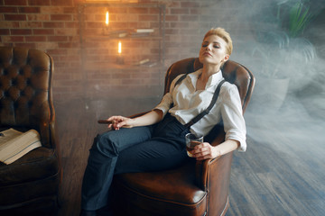 Woman sitting in chair with whiskey and cigar