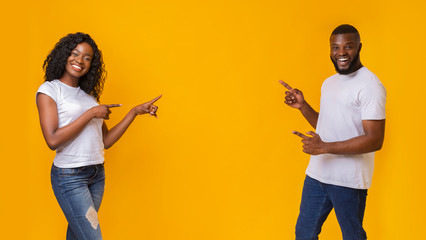African american man and woman pointing at empty space