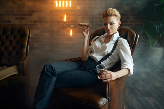 Woman sitting in chair with whiskey and cigar