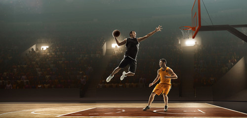 Two basketball players in action fighting for the ball near hoop