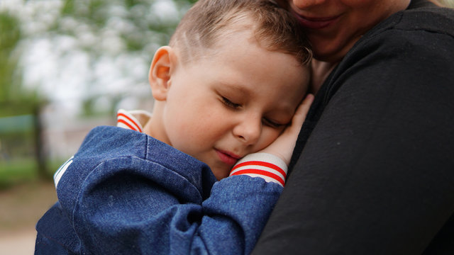 Smiling Woman Hug Cute Little Boy On Playground. Boy Close Eyes