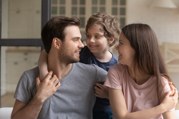 Cute little preschool boy embracing two smiling loving parents.