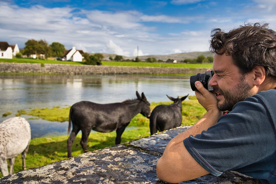 young photographer taking pictures of landscape with animals