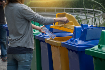 Tourists dropped plastic bottles putting in recycling bin in the park separating waste. Different trash can with colorful garbage bags. Earth day recycling concept