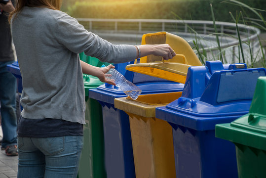 Tourists Dropped Plastic Bottles Putting In Recycling Bin In The Park Separating Waste. Different Trash Can With Colorful Garbage Bags. Earth Day Recycling Concept