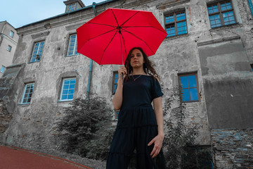 A gothic girl holding red umbrella outdoors