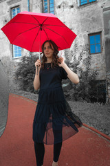 A gothic girl on the street with a red umbrella