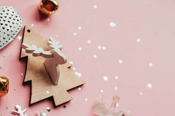 wooden christmas tree with deer and bells on a pink background. flat lay with christmas toys.