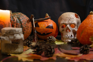 ceramic skull, pumpkins, candle and autumn leaves on a dark background, halloween background, copy space, burning candle