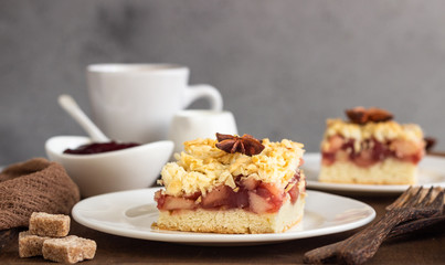 Apple, red berry jam and spices crumble topping cake and cup of coffee on wooden tray.