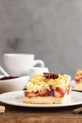 Apple, red berry jam and spices crumble topping cake and cup of coffee on wooden tray.