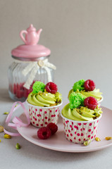 Set of pistachio cupcakes decorated with fresh raspberries on neutral color background