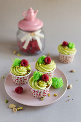 Set of pistachio cupcakes decorated with fresh raspberries on neutral color background
