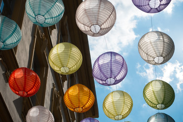 Lanterns of many colors hang in the German city of Wurzburg Decorations are backlit against a blue sky in this street scene viewed from below - Image