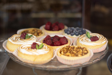 mini tart with fresh fresh raspberries and blueberries, peanuts and caramelon a large glass tray, food closeup