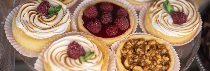 mini tart with fresh fresh raspberries and blueberries, peanuts and caramelon a large glass tray,...