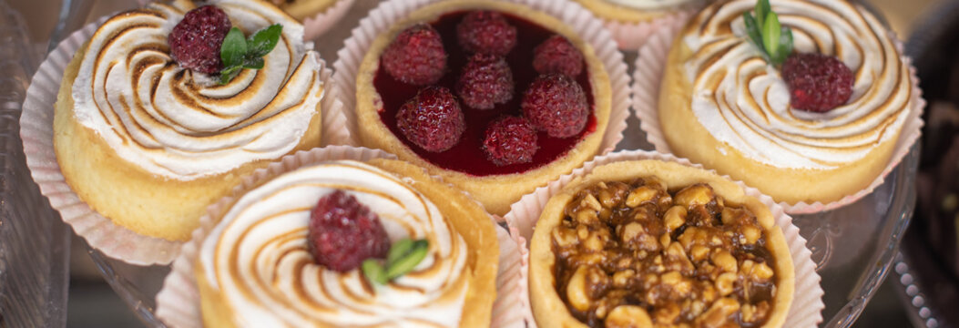 mini tart with fresh fresh raspberries and blueberries, peanuts and caramelon a large glass tray, food closeup. Long banner format. Header for web site.