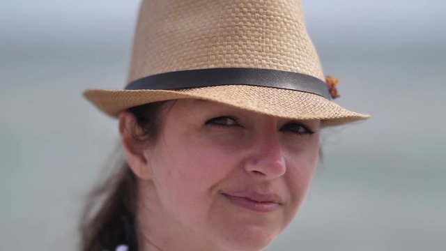 Portrait of a happy girl in a hat looks at the camera and smiles slow motion