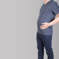 fat man with belly fat excess hand on abdomen isolated on grey backgroud