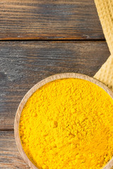 Turmeric powder in a wooden bowl on a wooden table. Top view. Place for text