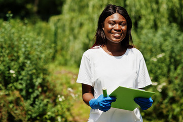 African volunteer woman with clipboard in park. Africa volunteering, charity, people and ecology concept.