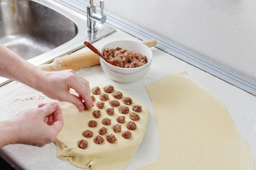 Dumplings with minced meat sculpts cook in the kitchen. Prepare homemade dumplings on the table, sprinkled with flour. Homemade meat dumplings. Sculpt dumplings.