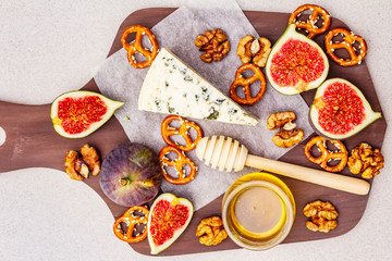Cheese platter (board) with blue cheese, honey, walnuts, figs, pretzels