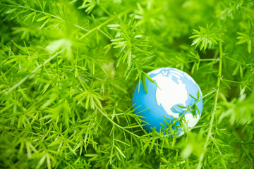 Global Warming, Environment and Ecology Concept. Close up of mini world ball on green leaf tree nature with rain drop.
