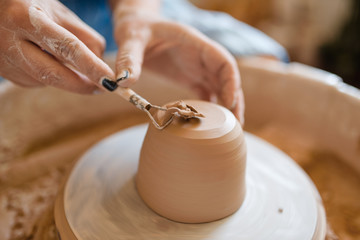 Female potter removes the extra layer on pot