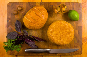 national Adyghe cheese homemade on a cutting Board with a knife, Basil, parsley, lime, sesame oil,...