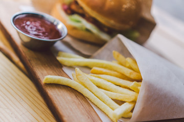Fresh tasty burger and french fries on wooden table. french fries and bbq sauce on wood plate. street food burger and fried potatoes. Unhealthy food. fast food and unhealthy eating concept