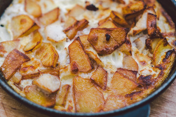 Potatoes baked with meat in the oven. Delicious dinner recipe. Potato pudding. Baked potato. Beef casserole. Potato gratin.Baked potatoes with eggs and chicken in a round bowl on a wooden table