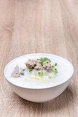 Thai food boiled rice porridege with pork in white bowl on wood table