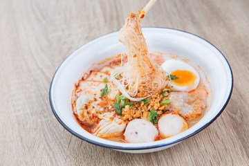 Thai Food noodle Tom Yum Bo Ran spicy in galvanized iron bowl chopsticks on wood table traditional local thai street food