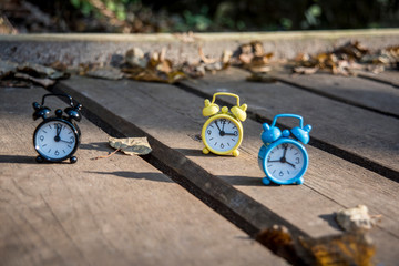 Vintage black alarm clock on autumn leaves. Time change abstract photo. Daylight saving time.