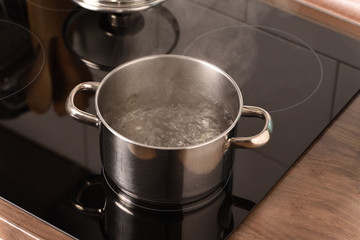 Boiling water in a pot on the black electric stove