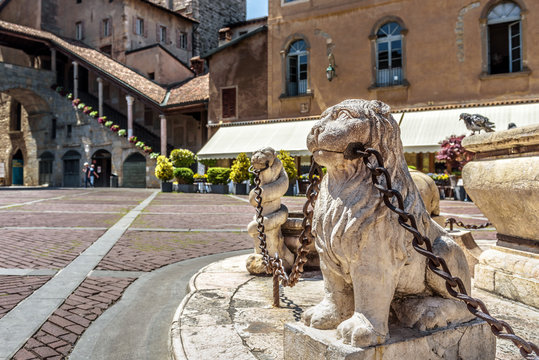 Piazza Vecchia in Citta Alta or Upper Town in Bergamo, Italy. Lion statues with chains at the vintage fountain.
