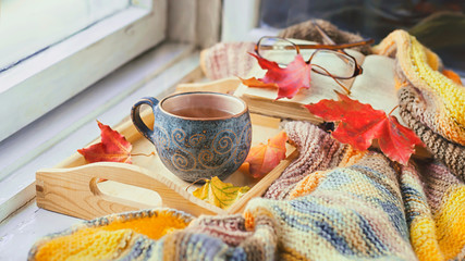 Cozy morning at home. A cup of tea, a blanket, old books and jelly on the windowsill.