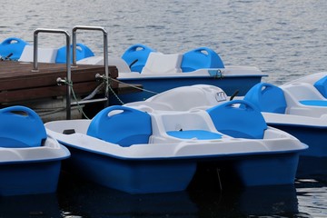 Pedal boats parked in a row on pond