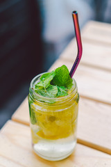 lemonade cocktail garnished with lemon and mint On Table. non alcoholic drink in vintage mason jar...