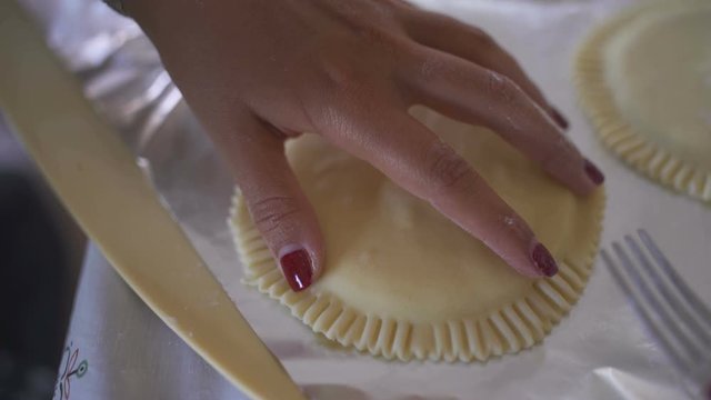 Woman cook closing ravioli with a fork. Cooking seadas, typical dessert of Sardinia, Italy.