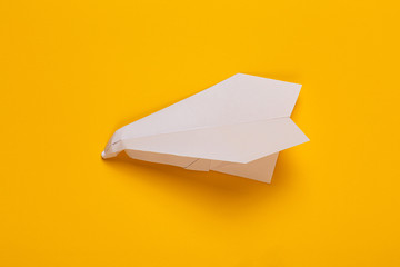 crumpled white paper airplane on a yellow background