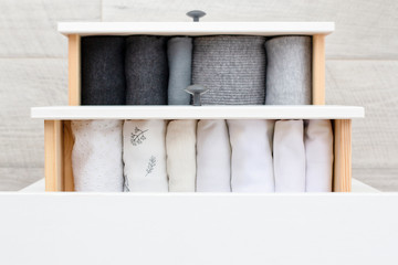 two open drawers with women's clothing in white and different shades of gray cotton and wool on the...
